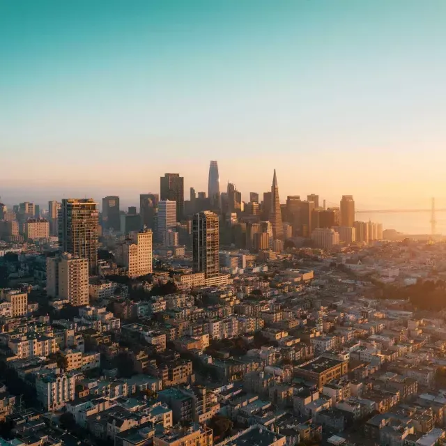 The sky行 of San Francisco is seen from the air in a golden light.